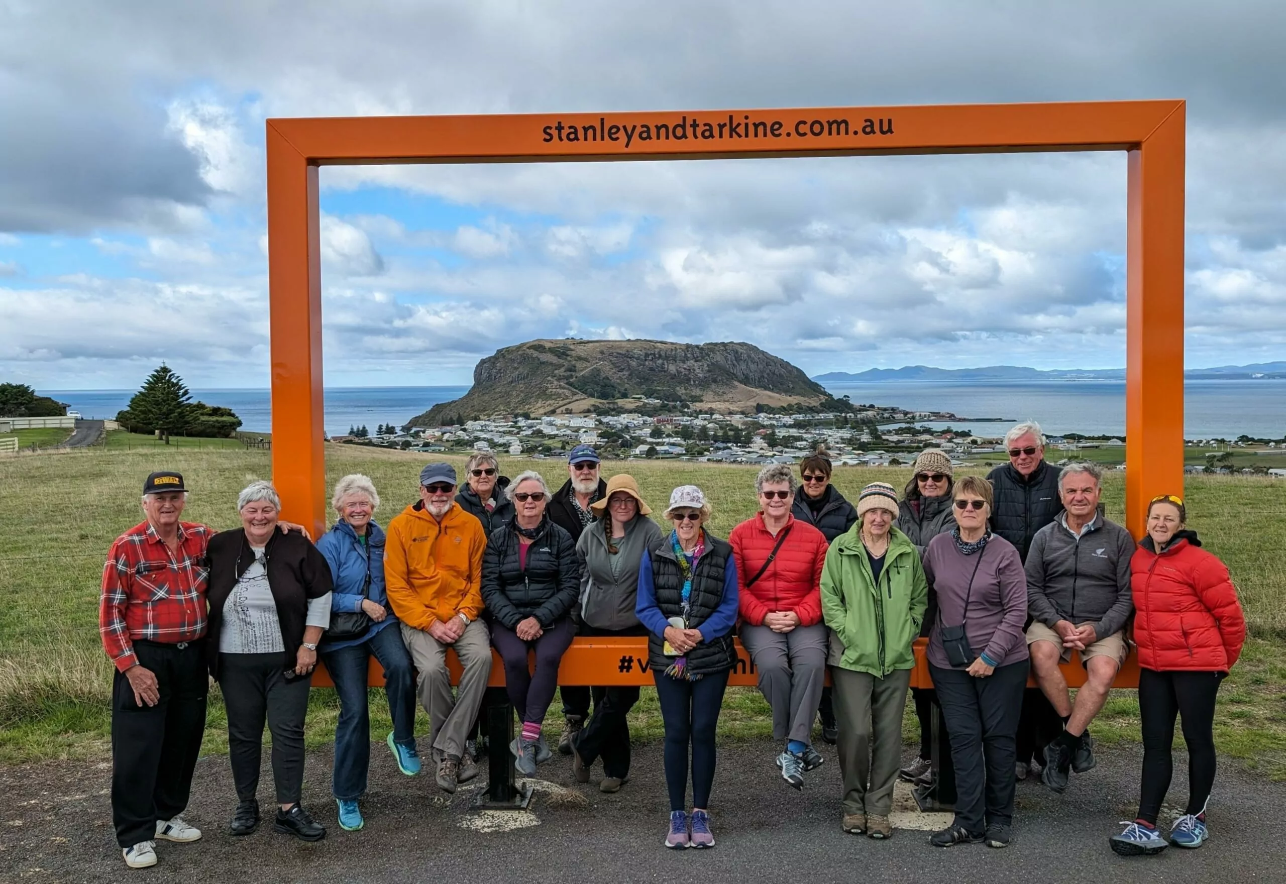 A group pose in the photo frame of Stanley in North West Tasmania. The Stanley Nut is visible in the background with the village just in front of it.